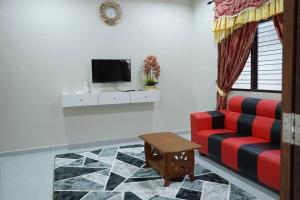 a living room with a red couch and a tv at ZZ Homestay in Bukit Payong