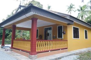 a yellow and red house with a balcony at ZZ Homestay in Bukit Payong