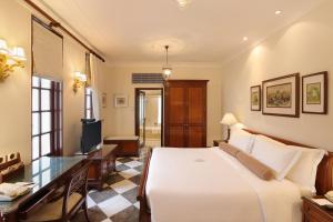Dormitorio con cama, escritorio y TV en The Imperial, New Delhi en Nueva Delhi