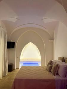 een slaapkamer met een groot bed en een gewelfd raam bij Zahra Superior Suite with private pool in Sannicola