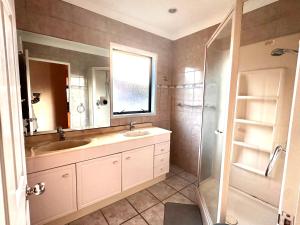 a bathroom with a sink and a shower and a mirror at West Harbour White House (西港白宫） in Auckland
