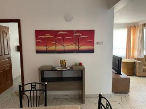 a living room with a table and a painting on the wall at Pinebreeze Holiday Resort in Nyali