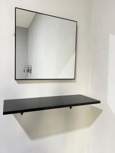 ein Spiegel an einer Wand mit einem schwarzen Regal in der Unterkunft Modern Style Village House in Kuching