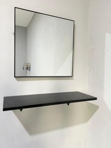 a mirror on a wall with a black shelf at Modern Style Village House in Kuching +16 photos