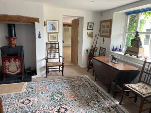 a living room with a table and a wood stove at Field End House in Cirencester