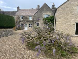 una casa con flores púrpuras delante de ella en Field End House en Cirencester