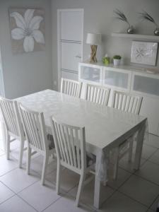 een witte eettafel met witte stoelen eromheen bij Jolie maison moderne et sereine à Labenne in Labenne
