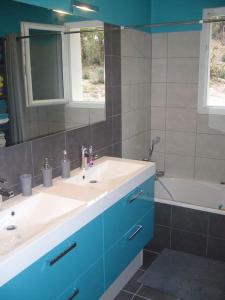 een badkamer met een wastafel, een spiegel en een bad bij Jolie maison moderne et sereine à Labenne in Labenne