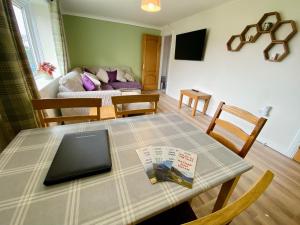 a table with a laptop on it in a living room at cosy town bungalow in Inverlochy