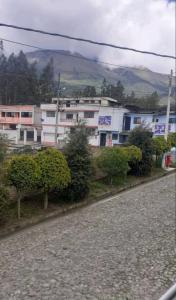 ein weißes Gebäude mit Bäumen vor einer Straße in der Unterkunft Casa Apartamento Campestre en las Faldas del Tayta Imbabura in San Juan de Ilumán