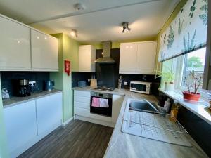 a kitchen with white cabinets and a sink at cosy town bungalow in Inverlochy