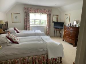 a bedroom with two beds and a dresser and a window at Field End House in Cirencester
