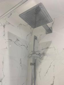baño con luz de ducha y paredes de mármol blanco en Guesthouse in Central Fleet, en Fleet