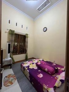 1 dormitorio con 1 cama con manta morada en Guesthouse Eldys, en Gondowulung