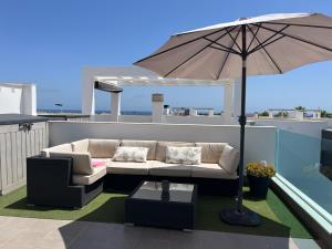 a patio with a couch and an umbrella at Casa Punta Prima III in Orihuela Costa