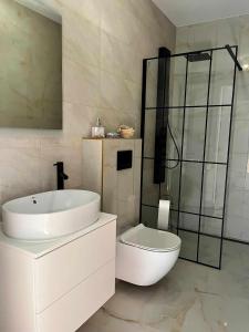 a white bathroom with a sink and a toilet at Bałtyckie Klimaty in Stegna