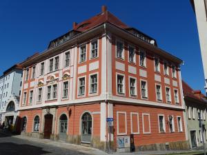 un edificio naranja y blanco en la esquina de una calle en Stadtpalais Merkur-Apartment maximal 2 Personen, en Bautzen