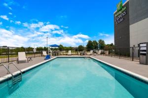 a swimming pool with chairs and a building at Holiday Inn Express & Suites - Springdale - Fayetteville Area in Springdale