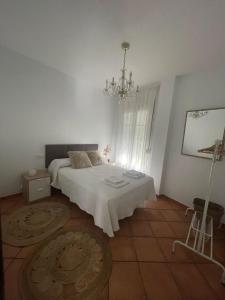 a white bedroom with a bed and a chandelier at Apartamentos La Palma in Ubrique