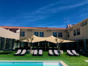 a hotel with chairs and a pool in front of a building at Estremoz Hotel in Estremoz
