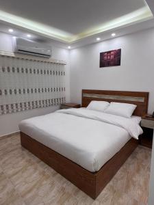 een slaapkamer met een groot bed met witte lakens bij Petra Family Hotel in Wadi Musa