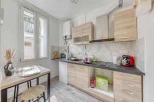 a kitchen with wooden cabinets and a table with chairs at Appartement Moderne, proche Porte de Versailles et Gare de Clamart in Malakoff