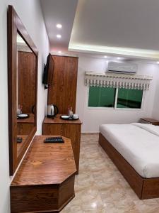 1 dormitorio con cama y mesa de madera en Petra Family Hotel, en Wadi Musa