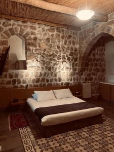 a bedroom with a large bed in a stone wall at Domaine de Chouchene in Şaḩrat al Qashsh