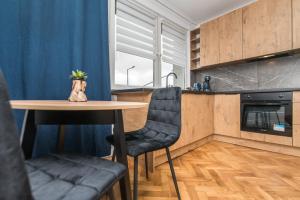 eine Küche mit einem Tisch, 2 Stühlen und einem Tisch mit einer Pflanze in der Unterkunft Apartament Jagielońska 1/3 in Gliwice