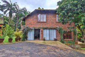 a brick house with a driveway in front of it at CASTLE COTTAGE Self catering fully equipped homely 120sqm double story king bed cottage in a lush green neighborhood in Hillcrest