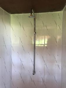a shower in a bathroom with a white tiled wall at AFLII Beach Club ( Zanzibar Beach ) in Mtwara
