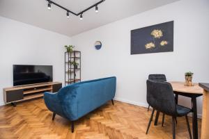 ein Wohnzimmer mit einem blauen Sofa, einem Tisch und Stühlen in der Unterkunft Apartament Jagielońska 1/3 in Gliwice