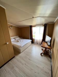 1 dormitorio con cama, escritorio y ventana en Sanjyra hostel, en Karakol