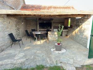 un patio con mesa, sillas y chimenea en Božini dvori, en Drniš
