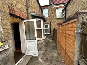 a white door in a brick building with a fence at The Griffen Lodge in Plumstead