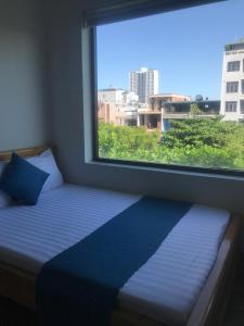 a bed in a room with a large window at Bao Tran Homestay in Danang