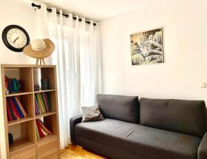 a living room with a couch and a clock on the wall at Un grand deux pièces in Charenton-le-Pont