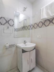 Baño blanco con lavabo y espejo en Hotel Grace, Karol Bagh, New Delhi en Nueva Delhi