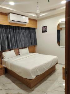 a bedroom with a bed with a tv on the wall at HOTEL LAVISH in Ahmedabad