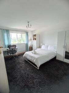 a white bedroom with a bed and a chair at Large family home near Richmond Park in New Malden