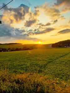 un campo de hierba con la puesta de sol en el fondo en Gasthof Sonnental en Winterberg