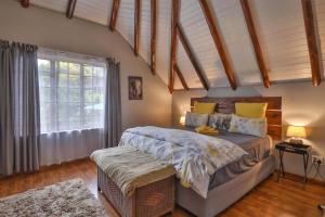 Un dormitorio con una cama grande y una ventana en CASTLE COTTAGE Self catering fully equipped homely 120sqm double story king bed cottage in a lush green neighborhood, en Hillcrest