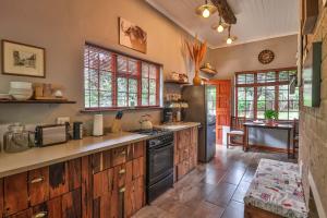 a kitchen with wooden cabinets and a stove top oven at CASTLE COTTAGE Self catering fully equipped homely 120sqm double story king bed cottage in a lush green neighborhood in Hillcrest