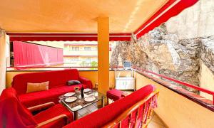 balkon z czerwoną kanapą i stołem w obiekcie los Gigantes Jardines del Mar w mieście Puerto de Santiago