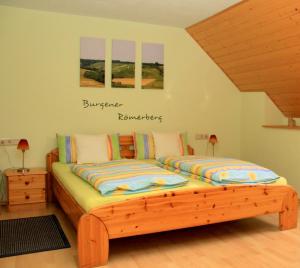 ein Schlafzimmer mit einem Holzbett mit zwei Kissen in der Unterkunft Ferienweingut & Gutsrestaurant Becker in Burgen