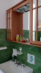 Romantic Casa Rurale Le Masche في Rivara: حمام أخضر مع حوض ومرآة