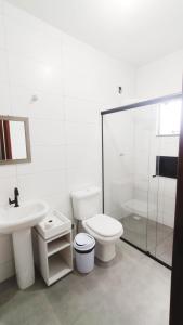 a bathroom with a toilet and a sink and a shower at Suítes do Vale - Praia do Rosa in Imbituba