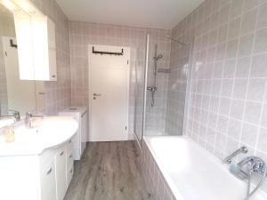 een badkamer met een bad, een wastafel en een douche bij Ferienwohnung Rheintal in Kappel-Grafenhausen