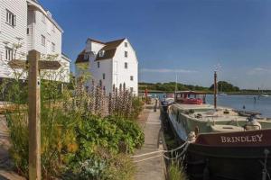 a boat parked next to a building and a house at Kingfisher Cottage - Woodbridge in Woodbridge