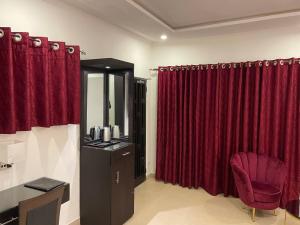 a bathroom with red curtains and a vanity and a chair at HOTEL LES ARCADES in Abomey-Calavi